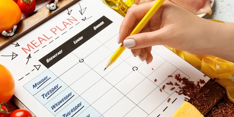 Person holding pencil above a paper for meal planning